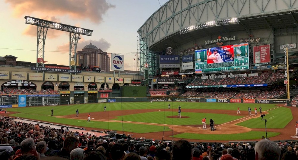 This image shows a baseball game in progress at a stadium with a large crowd of spectators. The stadium has a retractable roof open.